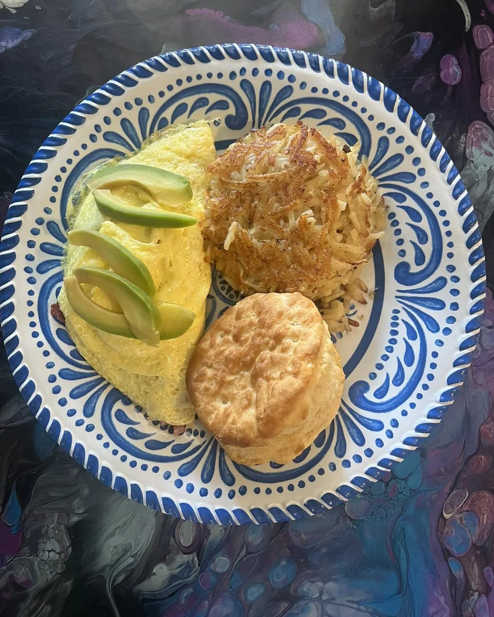 Avocado omelet with hash browns and a biscuit