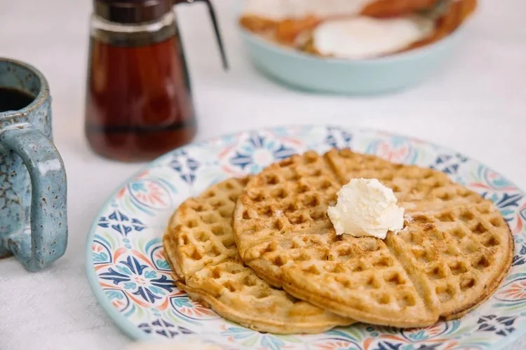Buttermilk waffles with butter next to a coffee carafe